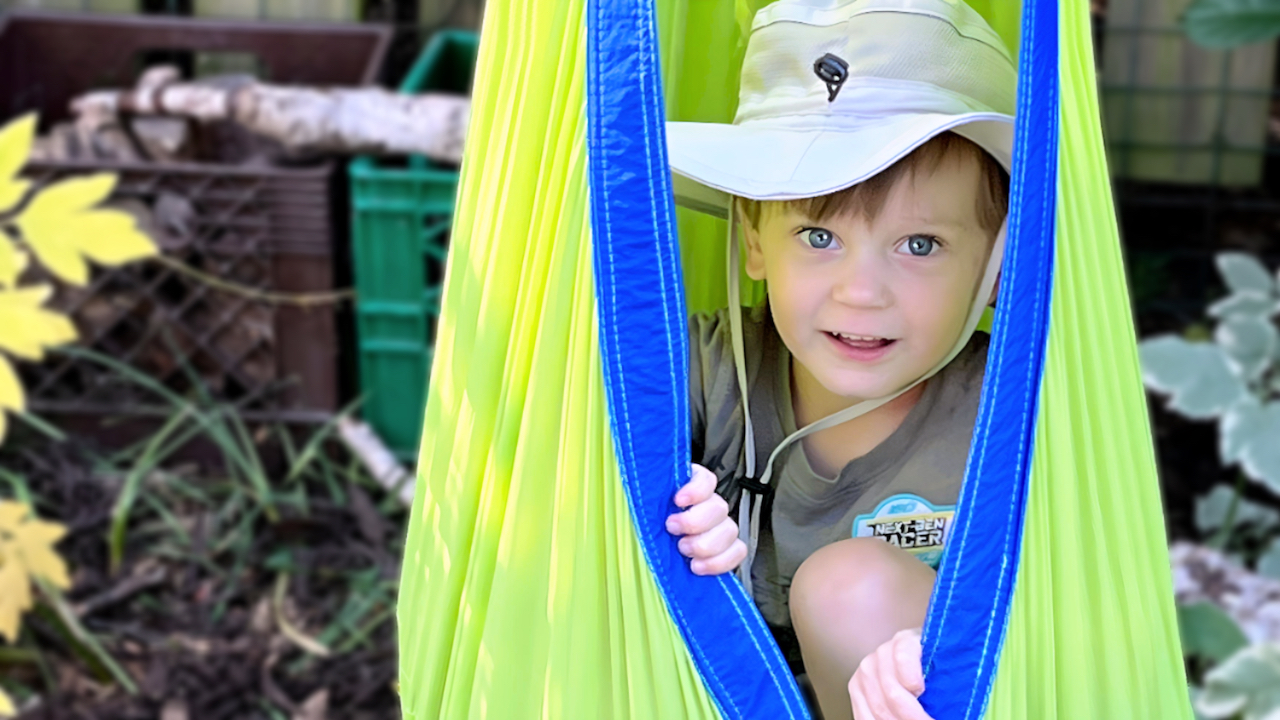 Boy relaxing in outdoor hanging nook at family child care